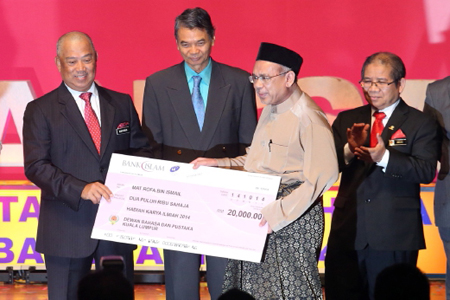 Timbalan Perdana Menteri, Tan Sri Muhyiddin Mohd Yassin (kiri) menyampaikan replika cek kepada pemenang hadiah Karya Ilmiah Sains Dan Teknologi 2014, Mat Rofa Ismail di majlis pelancaran Bulan Bahasa Kebangsaan Peringkat Kebangsaan 2014 di PICC. (sumber:w